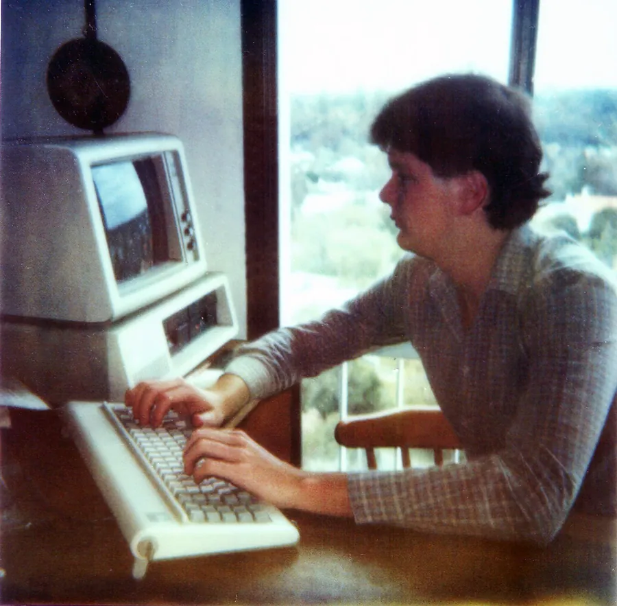 Nathan Buzza at fourteen, programming on the 1984 IBM PC his father bought him after brain surgery — the machine on which Data World began.